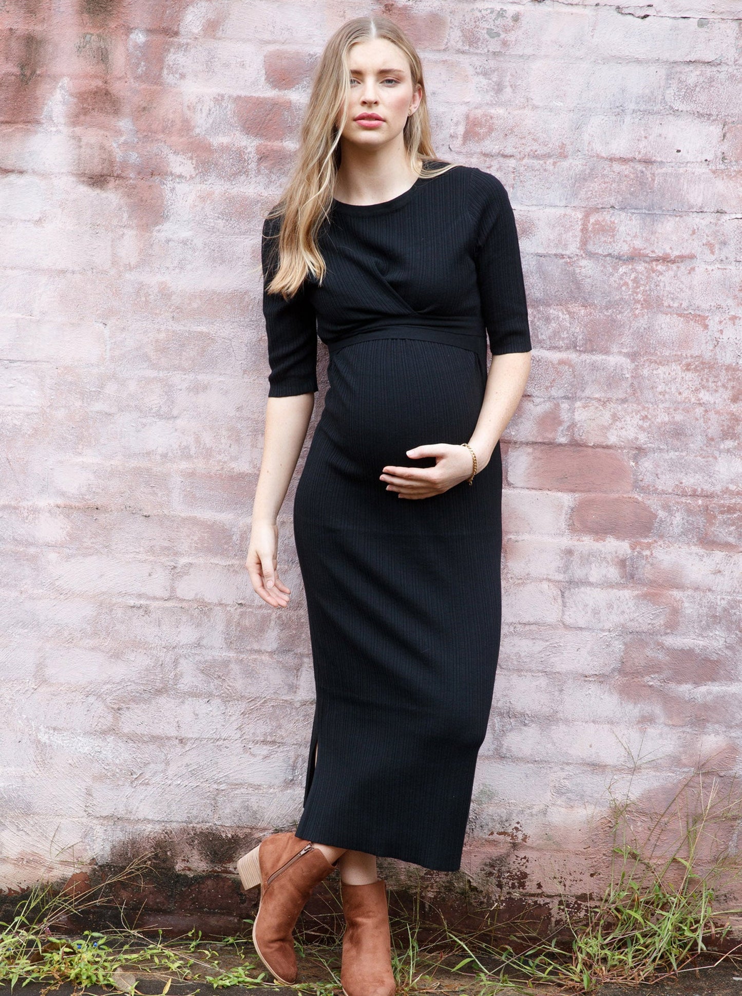 A woman in black angel maternity annabella knit dress against the wall (6594399666279)